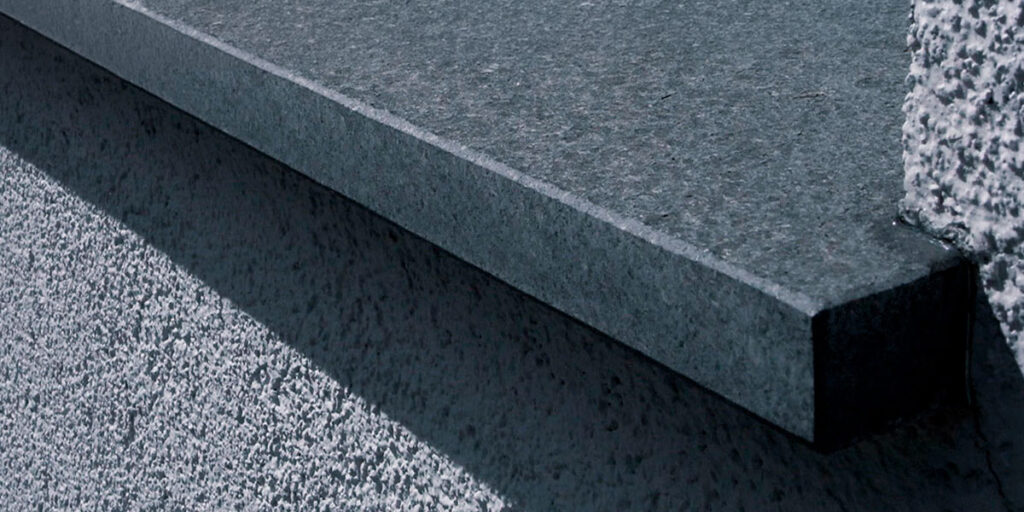 Hochwertige Granit-Fensterbank an einer dunkelgrauen Fassade – stilvolle Fassadengestaltung mit langlebigen Materialien.