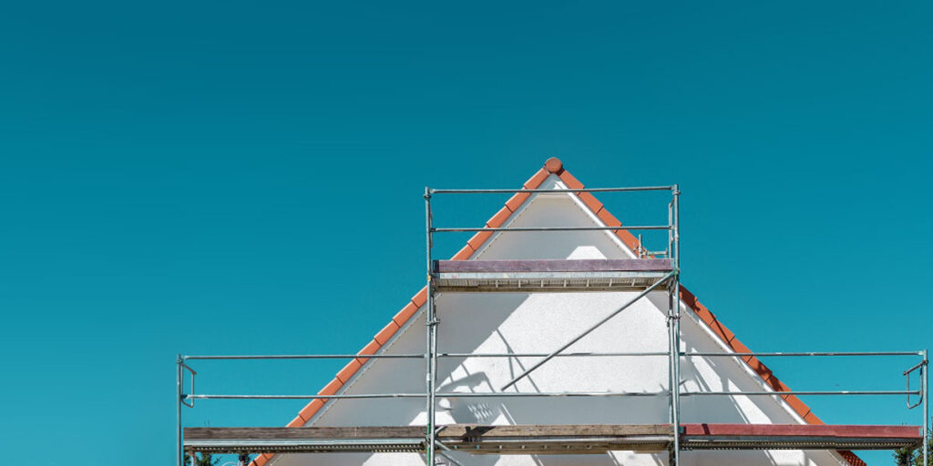 Eingerüstetes Einfamilienhaus während des Neuanstrichs eines weißen Holzgiebels durch den Malereibetrieb Freimann in Wennigsen.