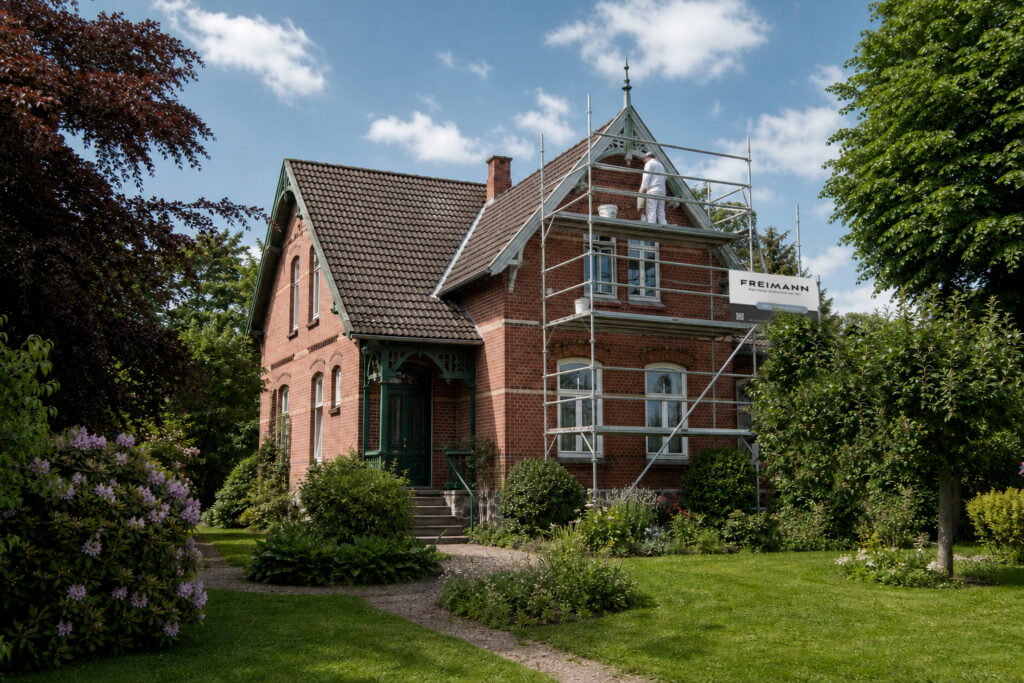 Denkmalgeschütztes Backsteinhaus mit Gerüst während der Malerarbeiten an den Holzteilen der Fassade durch den Malereibetrieb Freimann in Wennigsen.